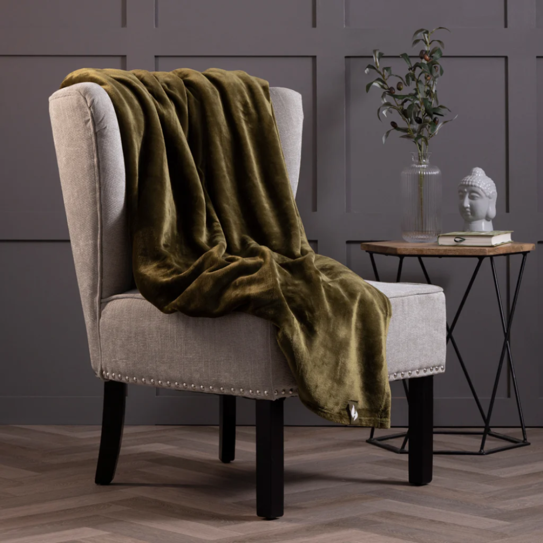 Olive Green thermal blanket draped over a  armchair and small table in the background.