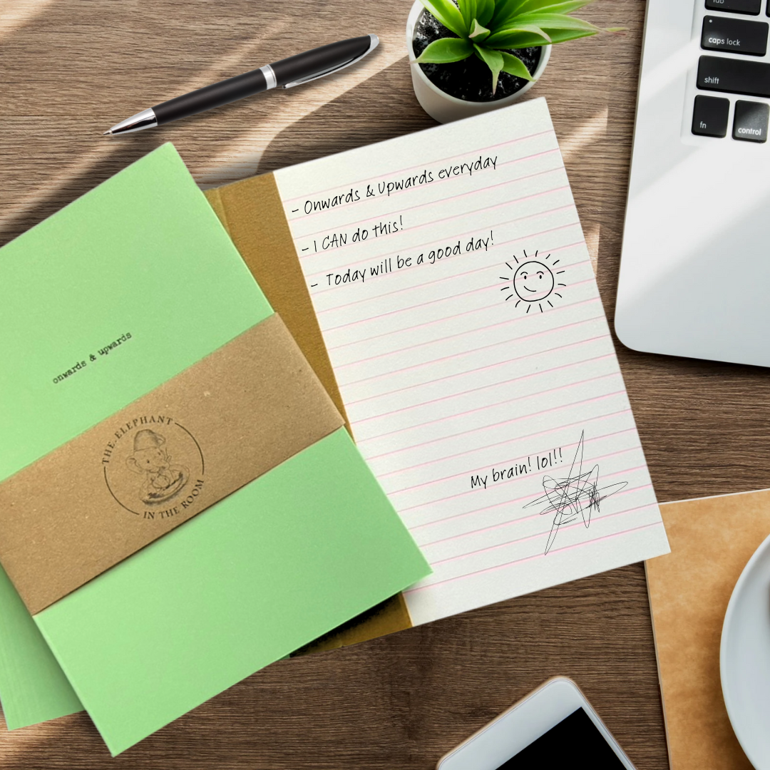 Green handmade notebook saying Onwards and Upwards on an open notebook showing lined pages.