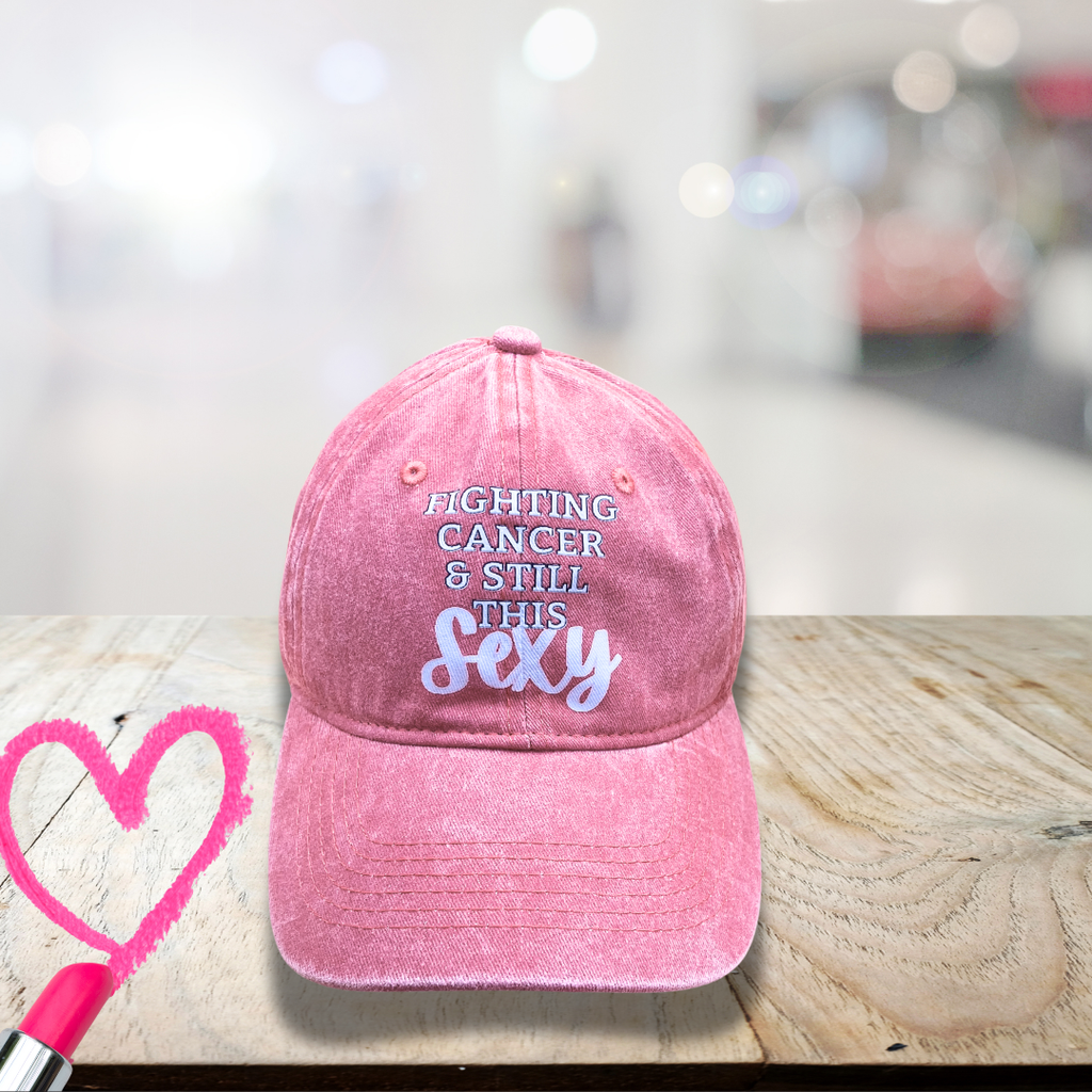 Pink cap with text 'Fighting cancer & still this sexy' to use as funny gifts for breast cancer patients.