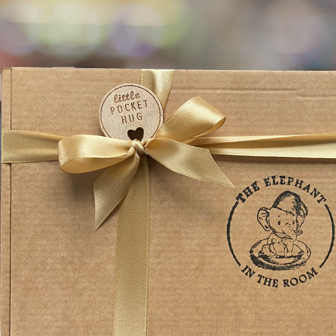 Gift box with a gold ribbon and 'Little Pocket Hug' tag, featuring 'The Elephant in the Room' branding.