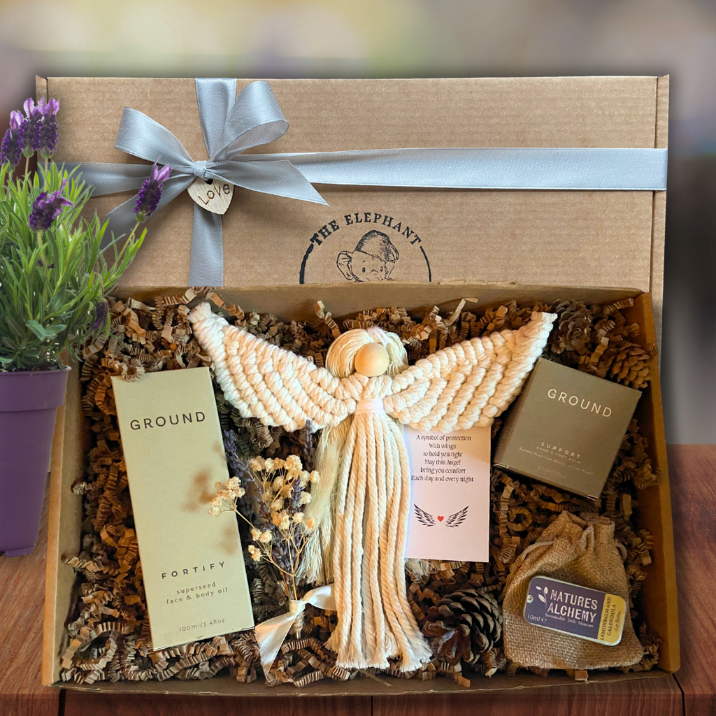Cancer Gift box with angel figurine, natural body and hand oils and nature-themed items on a wooden surface.