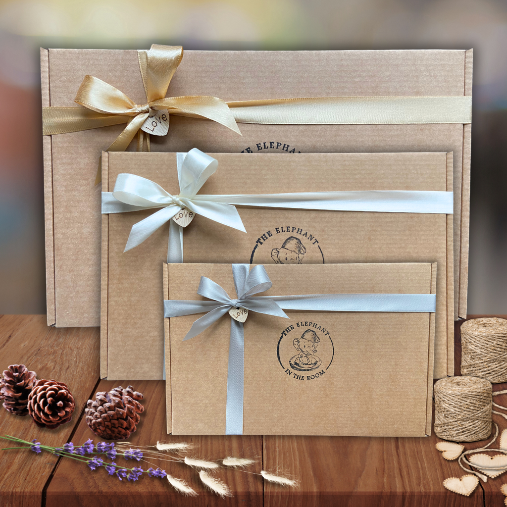 Three brown gift boxes to create your own care package with ribbons on a wooden surface with decorative elements.
