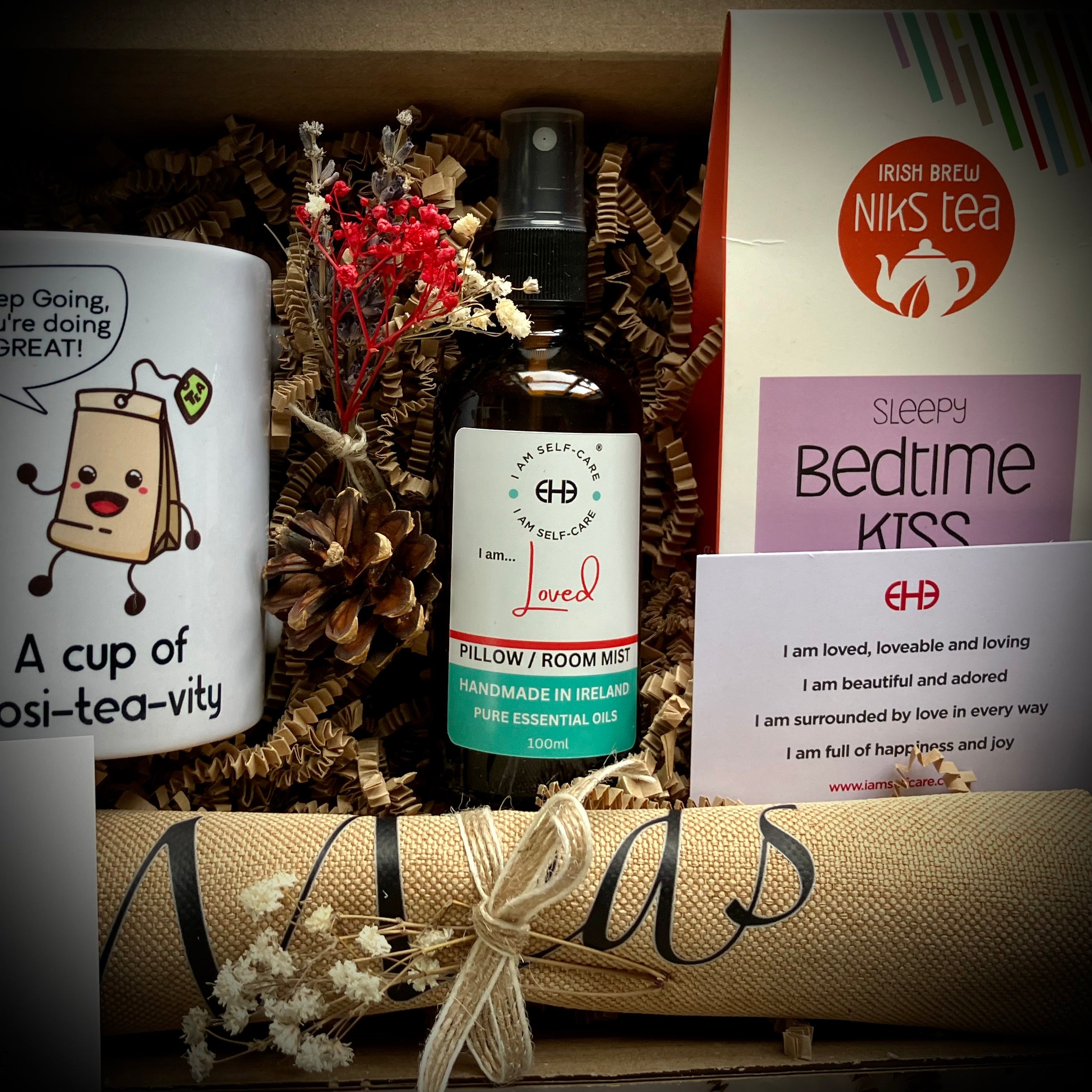 Gift set with a mug, essential oil bottle, and card on a wooden surface.