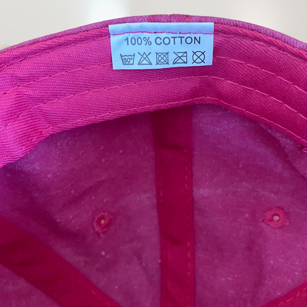 100% cotton label on pink baseball cap for cancer patients