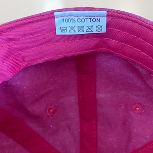 100% cotton label on pink baseball cap for cancer patients
