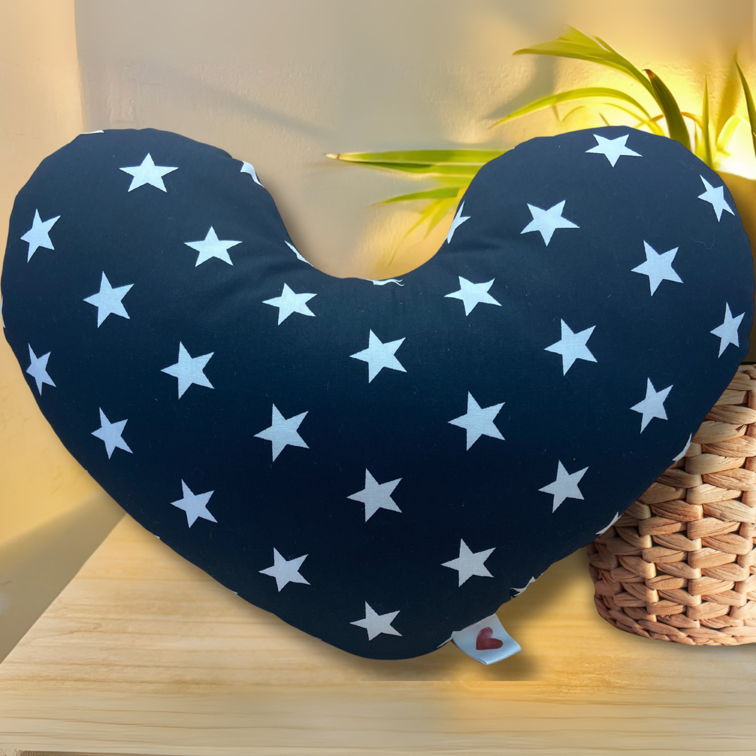 Black breast cancer pillow with white star pattern on a wooden surface.